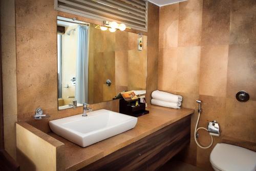 a bathroom with a sink and a mirror and a toilet at Adamo the Resort in Matheran