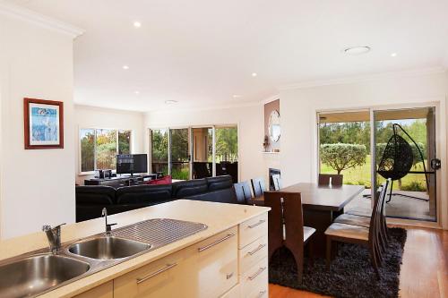 a kitchen and living room with a couch and a table at Peppertree Lodge Hunter Valley in Rothbury