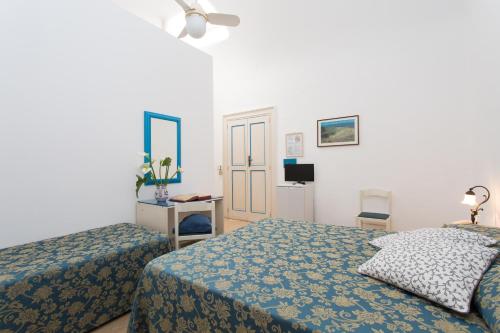 a bedroom with two beds and a desk and a television at Hotel Poseidon in Lipari