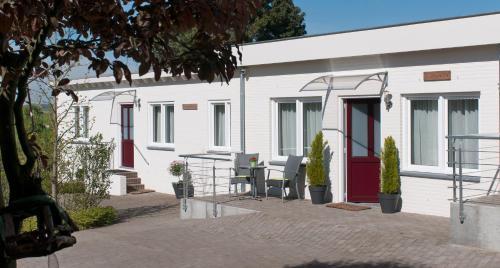 a white building with red doors and a table and chairs at Hotel Berg en Dal in Epen