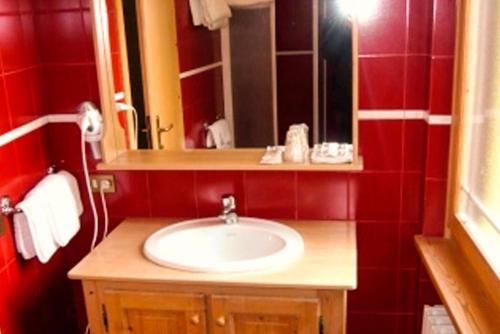 a bathroom with a sink and a red wall at Hotel Aurora srls in Auronzo di Cadore