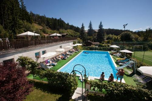 a large swimming pool with people standing around it at Hotel Scoiattolo in Baselga di Pinè