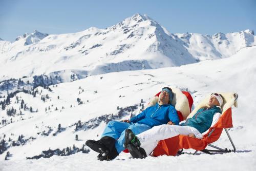 three people sitting in a chair in the snow at Apart6580 in Sankt Anton am Arlberg
