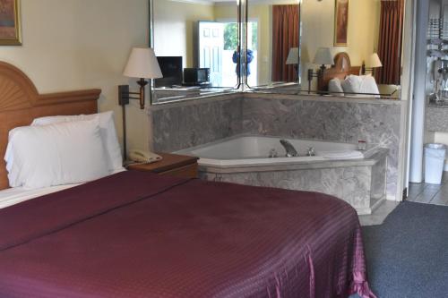 a hotel room with a bed and a bath tub at Star Inn Biloxi in Biloxi