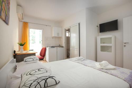 Una habitación blanca con una cama y una cocina. en Apartments Klara, en Makarska