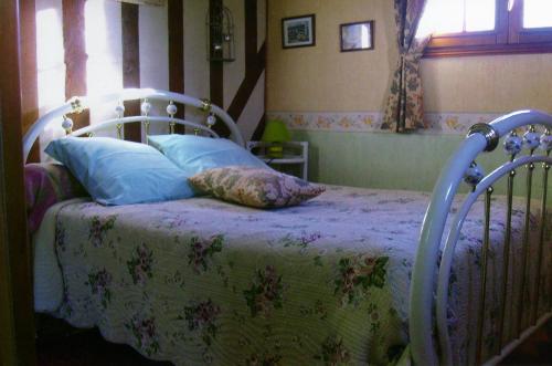 1 dormitorio con 1 cama con manta y almohadas en Chambre chez Corinne, en Fourneville