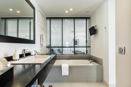 a bathroom with a tub and a large window at Hôtel Club Port La Galère in Théoule-sur-Mer