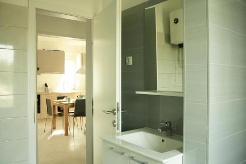 eine weiße Küche mit einem Waschbecken und einem Tisch in der Unterkunft Apartmani Japa in Vrsi