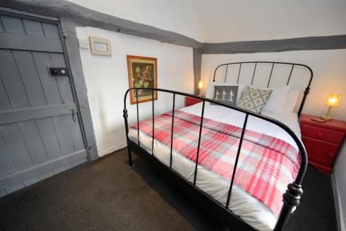 a bedroom with a black bed with a red blanket at The White Lion Inn in Hampton in Arden