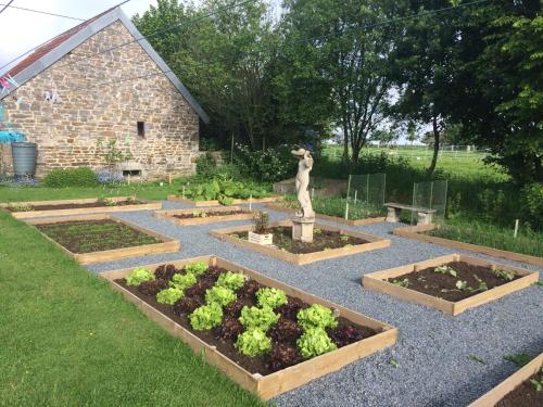 a garden with four raised beds of vegetables and a statue at La Crepelliere in Villedieu-les-Poëles