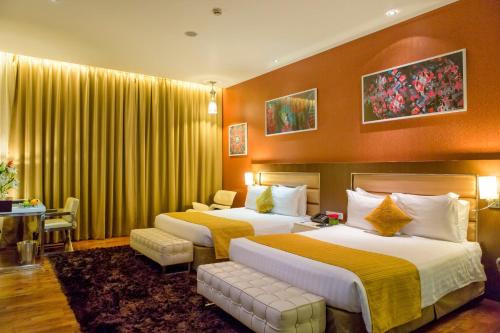 two beds in a hotel room with yellow curtains at The Deltin in Daman