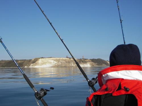 a person in a boat with a backpack and fishing rods at Gasthaus & Pension "Zur Schaabe" in Glowe