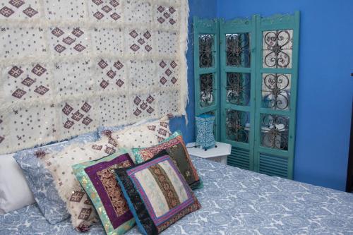 1 dormitorio con cama con almohadas y pared azul en Ca L'Isabel, en Villanueva de los Castillejos