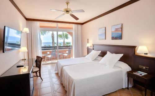 モロ・デル・ハブレにあるOccidental Jandía Playaのベッドとバルコニー付きのホテルルーム