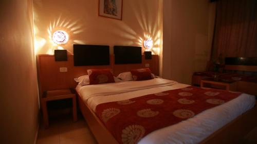 a bedroom with a bed and two lights on the wall at Hotel Les Palmiers in Monastir