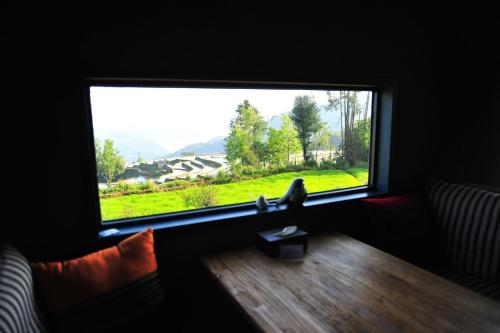 a bird sitting on a table in front of a window at The Twelve Manor•Terraces Lodge in Yuanyang