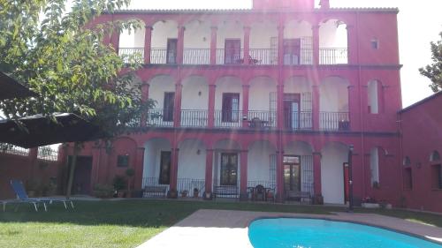 un gran edificio rojo con una piscina frente a él en Aparthotel Can Gallart, en Santa Coloma de Farners