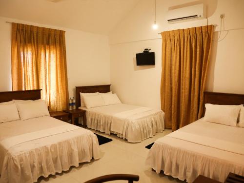 a hotel room with two beds and a television at Pasikudah Eco Village Hotel in Pasikuda