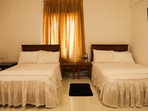 a bedroom with two beds and a window at Pasikudah Eco Village Hotel in Pasikuda
