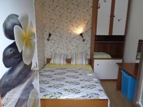 um pequeno quarto com uma cama e uma flor na parede em Apartments Kavan em Barbariga