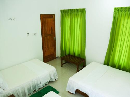 a room with two beds and green curtains at Pasikudah Eco Village Hotel in Pasikuda