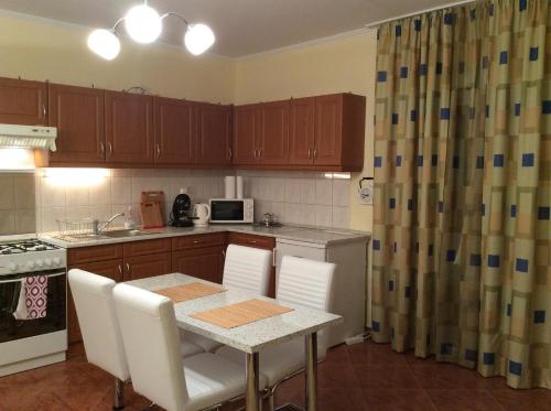 cocina con mesa con sillas blancas y cocina con fogones en Rehab Apartment, en Hévíz
