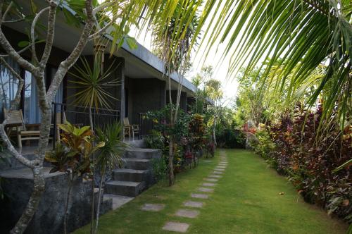 a house with a garden with a lawn and trees at Willy Homestay in Uluwatu