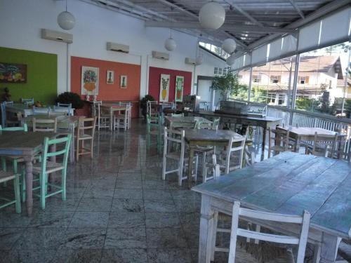 an empty restaurant with wooden tables and chairs at Center Suiço Flats in Campos do Jordão
