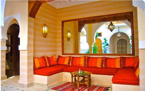 a living room with a red couch and a mirror at Riad Rabahsadia in Marrakech
