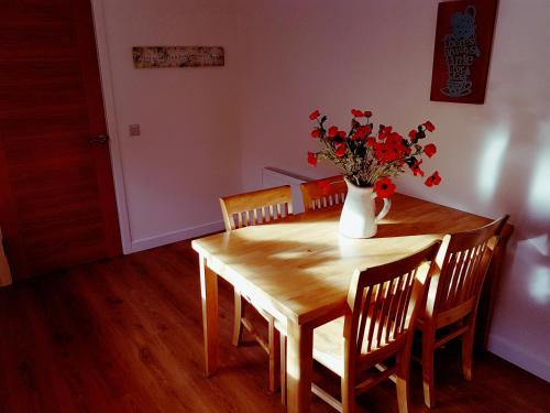 a dining room table with a vase of flowers on it at Yvi's 2Bedroom 2Bathroom Apartment in Inverurie