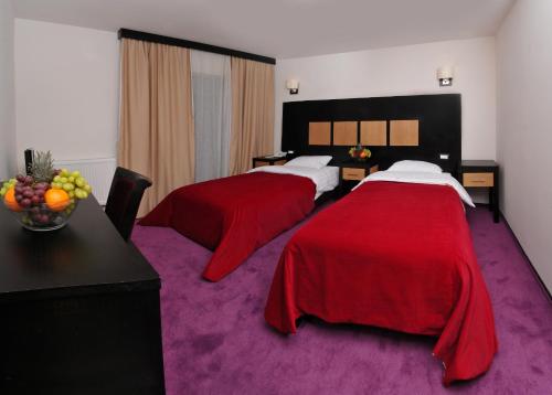 Habitación de hotel con 2 camas con colchas rojas en Hotel ToacaBellevue, en Gura Humorului