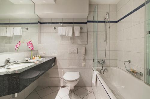 La salle de bains est pourvue d'une baignoire, de toilettes et d'un lavabo. dans l'établissement Kongress Hotel Davos, à Davos