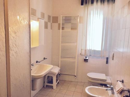 La salle de bains blanche est pourvue d'un lavabo et de toilettes. dans l'établissement Hotel 2 Magnolie, à Piancogno