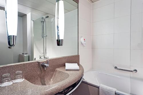a bathroom with a sink and a mirror at Tryp by Wyndham Wuppertal in Wuppertal