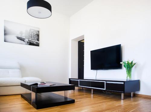 uma sala de estar com um sofá e uma televisão na parede em Red Brick Apartments em Klaipėda