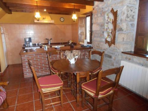 a dining room with a table and chairs and a kitchen at Casa El Prado de la Romia in Argüero