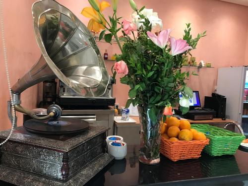 a table with a vase of flowers and a vase of oranges at Hotel AL KARMEL in Tunis