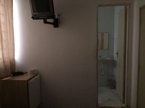 baño con TV en la pared y ducha en Hotel São João, en Campinas