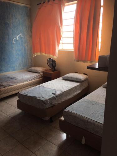 two beds in a room with orange curtains at Hotel São João in Campinas