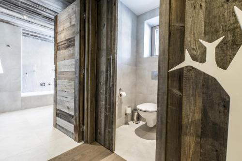 a bathroom with a toilet and a wooden door at Hôtel Spa Crychar in Les Gets