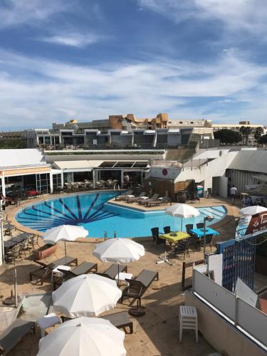 une piscine avec des parasols et des chaises et un bâtiment dans l'établissement Luxe appartement Village Naturiste Zébra, au Cap d'Agde