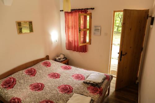 a bedroom with a bed with red roses on it at GRAB ethno village and camp in Šćepan-Polje
