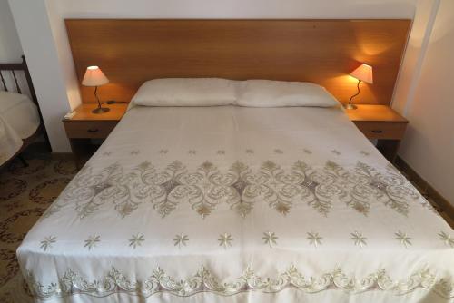 una camera da letto con un letto con copriletto bianco e 2 lampade; di Appartamento Petrarca a Gallipoli