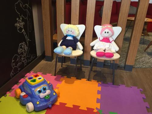 two toy teddy bears sitting on chairs in a room at ibis Joinville in Joinville