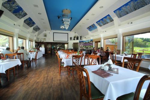 a restaurant with white tables and chairs and people sitting at tables at Osada Koszałkowo Wieżyca in Szymbark