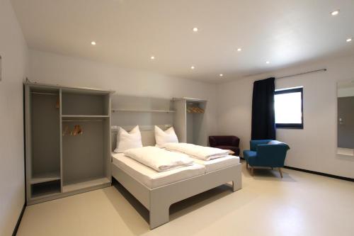 ein Schlafzimmer mit einem weißen Bett und einem blauen Stuhl in der Unterkunft Neumann's Übernachten in Plankstadt