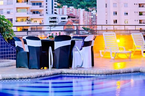 een tafel en stoelen naast een zwembad bij Hotel Obelisco in Cali