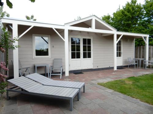 Dieses weiße Haus verfügt über eine Terrasse mit einem Tisch und Stühlen. in der Unterkunft De Waterlelie in Renesse