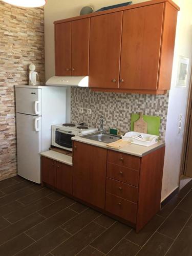 a kitchen with wooden cabinets and a sink and a refrigerator at Laura Beach House in Alykes