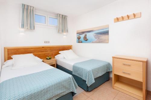 um quarto de hotel com duas camas e uma mesa em MUR Apartamentos Buenos Aires Gran Canaria em Playa del Inglés